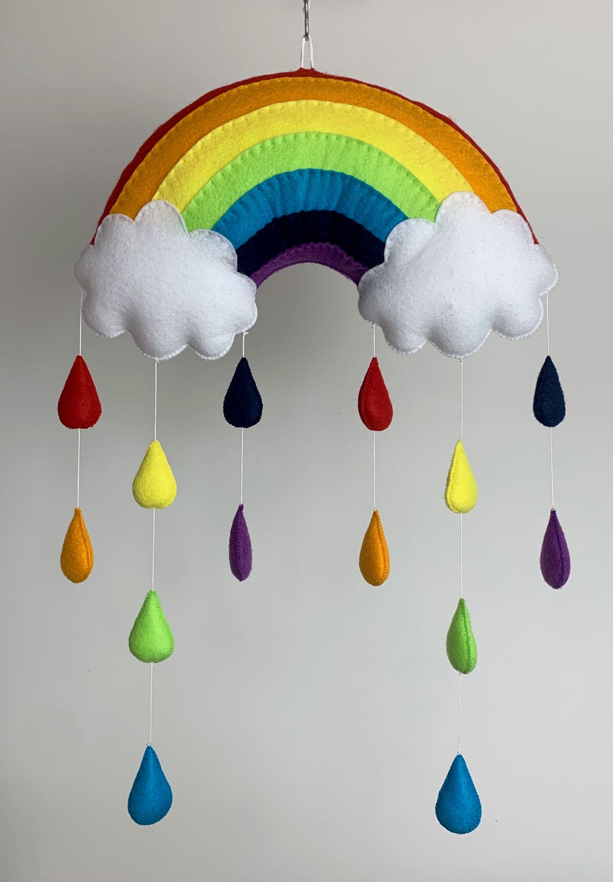 Suspension arc-en-ciel en feutrine entièrement fait main pour chambre d’enfant, avec motifs suspendus au choix : cœurs, étoiles ou gouttes de pluie. 